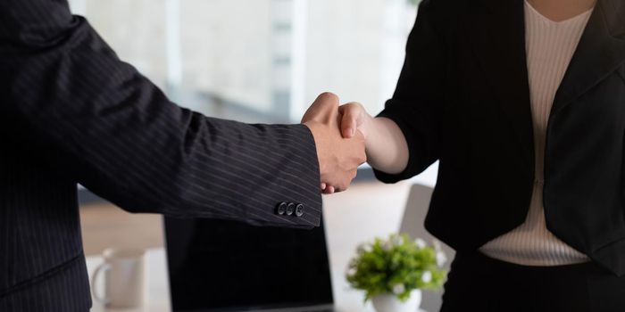 Business people handshake at meeting table in office together with confident . Young businessman and businesswoman workers express agreement of investment deal.