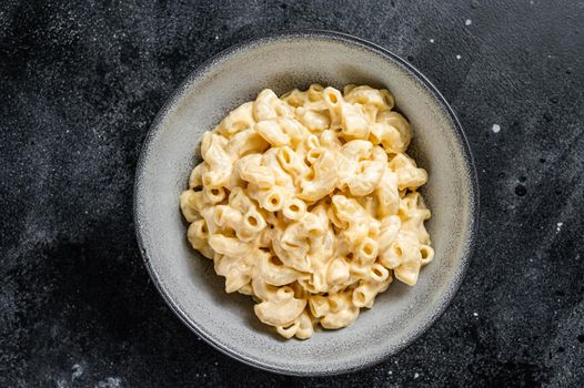 Mac and cheese american macaroni pasta with cheesy Cheddar sauce. Black background. Top view.