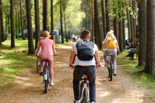 A group of cyclists with backpacks ride bicycles on a forest road enjoying nature.