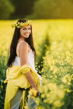 a woman enjoys a bike ride in a field full of bright yellow rapeseed.