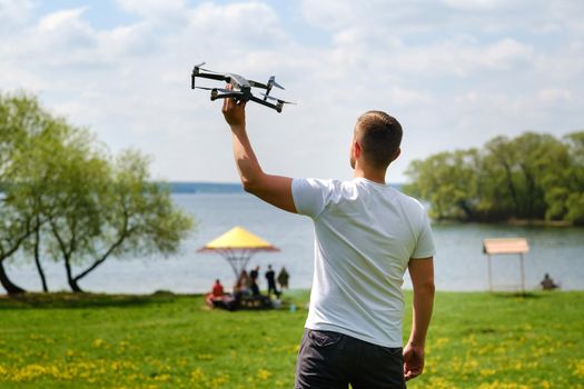 A man with a flying vehicle in his hands, raised to the sky in nature.Launching a drone.