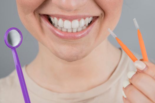 Close-up portrait of a smiling woman holding a brush and a dental mirror. Widescreen.