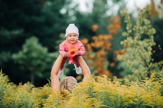 Happy time together. Mother playing with her baby, holding kid on hands