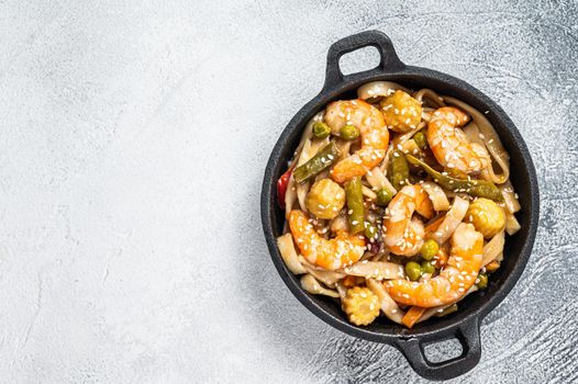 Udon stir-fry noodles with shrimps prawns in a pan. White background. Top view. Copy space.