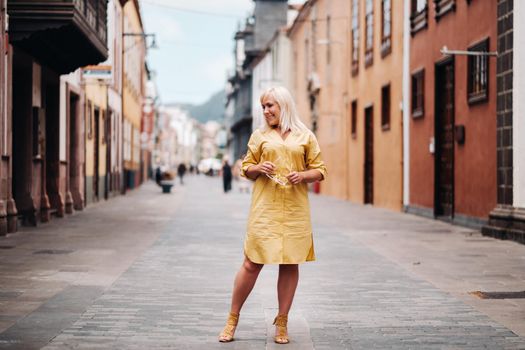 a blonde woman in a yellow summer dress stands on the street of the Old town of La Laguna on the island of Tenerife.Spain, Canary Islands.