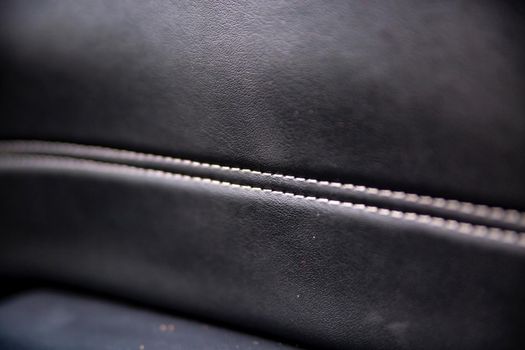 white trim on the black leather interior of a premium modern car. close-up. selective focus. no people