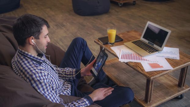 Manager headphones to communicate with clients using the tablet on the table is a laptop and documents lie.