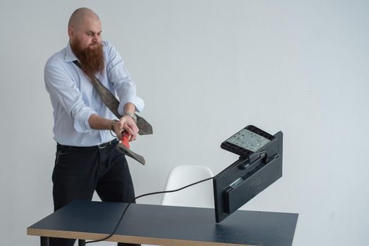 Stressed crazy businessman smashing his computer in office using ax problem concept. The man has problems at work and frustration