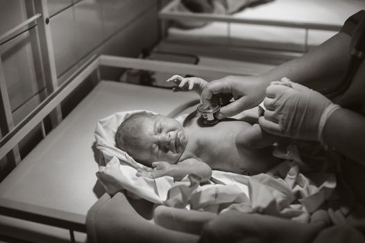 A pediatrician examines a child in the clinic, a newborn girl is lying on the table.Black and white photo.