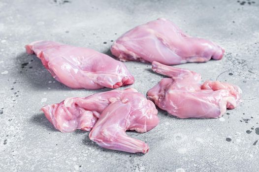 Raw rabbit legs slices on a butcher board. Gray background. Top view.