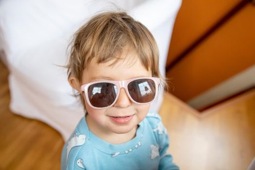 portrait of happy smiling adorable toddler in baby sunglasses. cheerful child playing