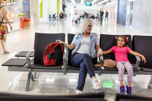 happy mother and daughter playing a game at airport before boarding