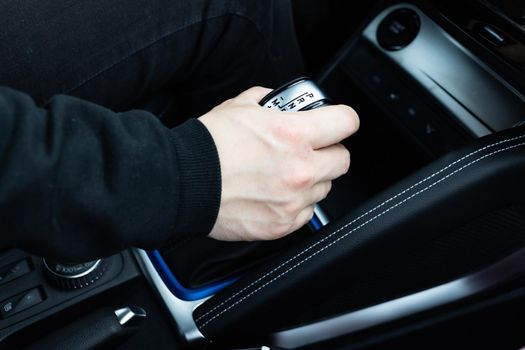 male hand shifts gears on the automatic transmission lever angle view