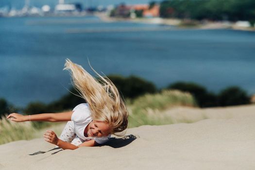 a child has fun in the sand dunes on the beach in Nida.Lithuania.