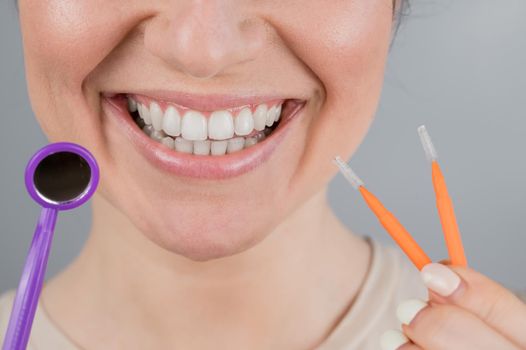 Close-up portrait of a smiling woman holding a brush and a dental mirror. Widescreen.