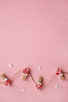 Christmas decorations decorative background. Decorative pins in the form of red gloves on a pink background. Top view, minimalism, flat lay.