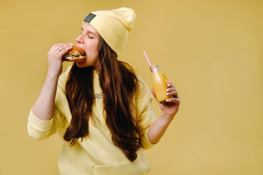 pregnant girl in yellow clothes with hamburgers in her hands on a yellow background.