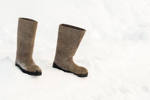 close up of felt boots standing in the snow.