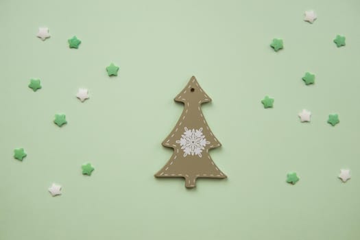 Christmas decorations decorative background. Decorative wooden white Christmas tree toy in the shape of a Christmas tree on a green background. Top view, minimalism, flat lay