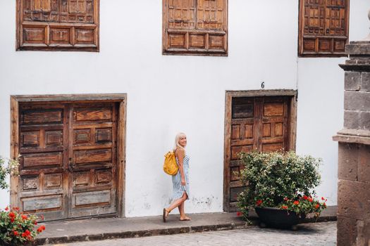 a blonde in a sundress with a backpack walks along the street of the Old town of Garachico on the island of Tenerife.Spain, Canary Islands