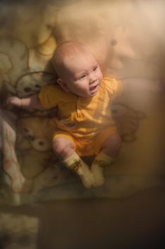 Beautiful smiling cute baby lying on the bedspread.