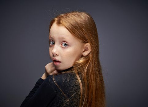 red-haired girl with freckles on her face in a black sweater posing. High quality photo