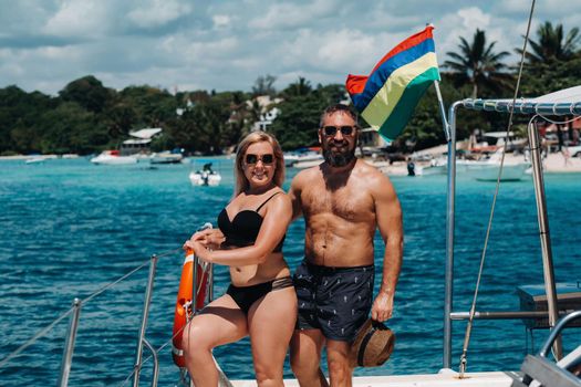 Smiling young couple looking at each other, standing on board the yacht