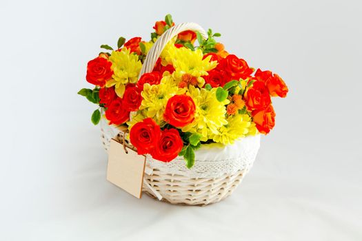 beautiful white basket with scarlet roses and yellow chrysanthemums. white background for cutting. card blank for the inscription copy space