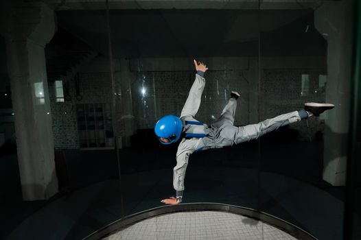 A young woman in overalls and a protective helmet enjoys flying in a wind tunnel. Free fall simulator.