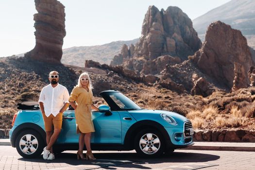 a woman and a man wearing glasses in a convertible car on a trip to the island of Tenerife. The crater of the Teide volcano, Canary Islands,Spain.