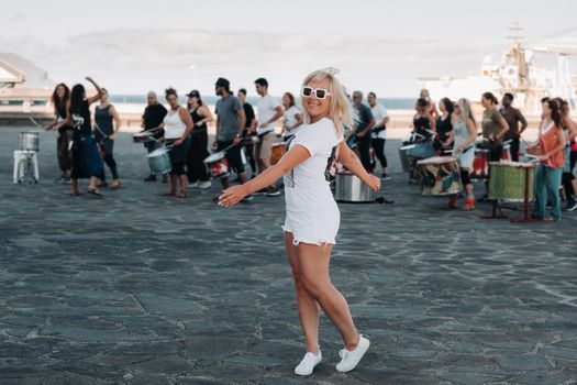 A girl in white clothes on the background of people engaged in fitness in the city of Santa Cruz de Tenerife on the waterfront. Canary Islands, Spain.