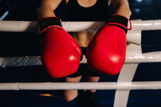 portrait of a female boxer in red gloves in the gym during training.