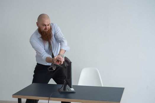 Stressed crazy businessman smashing his computer in office using ax problem concept. The man has problems at work and frustration