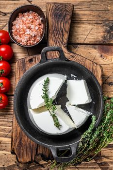 Fresh Ricotta cream Cheese in a pan with basil and tomato. wooden background. Top view.