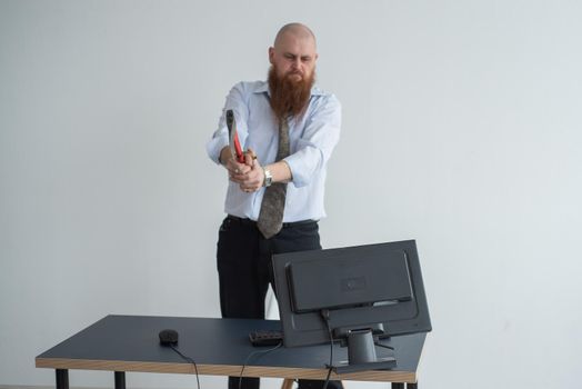 Stressed crazy businessman smashing his computer in office using ax problem concept. The man has problems at work and frustration