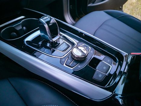 close up of multimedia system control and gearshift in interior of modern premium car/ no people. touch panel in a premium car. Management of multimedia functions, and options of the car, navigation, music. Cup holders and gear lever.