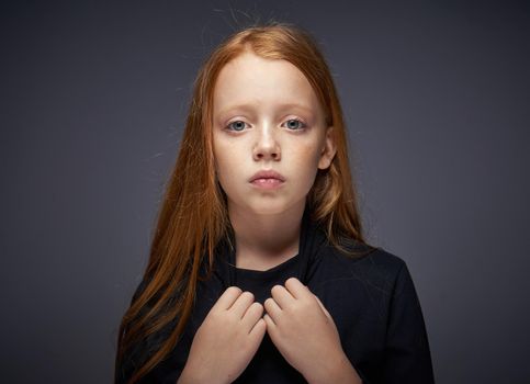 red-haired girl with freckles on her face in a black sweater posing. High quality photo