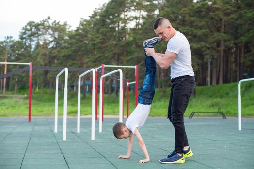 Caucasian man teaching son handstand at playground