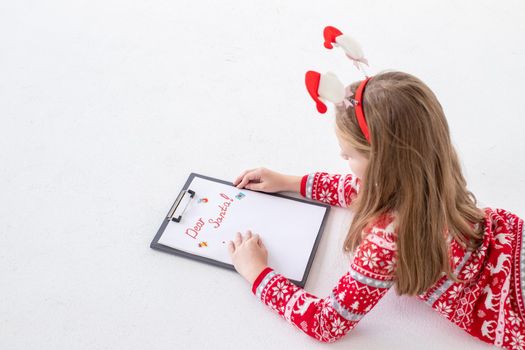 Child writing letter to Santa Claus at Christmas. Top view.