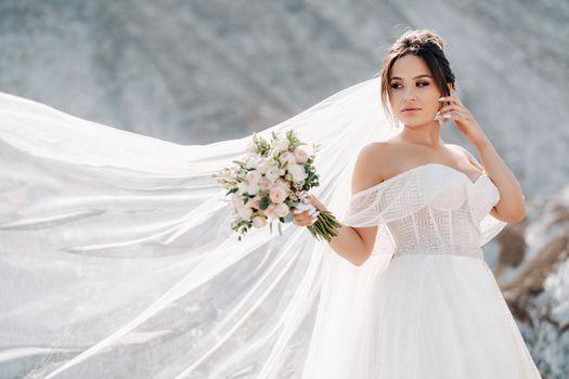 Beautiful bride in a wedding dress with a bouquet on the top of the salt mountains. A stunning young bride with curly hair . Wedding day. . Beautiful portrait of the bride without the groom