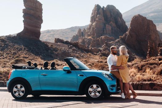 a woman and a man wearing glasses in a convertible car on a trip to the island of Tenerife. The crater of the Teide volcano, Canary Islands,Spain.