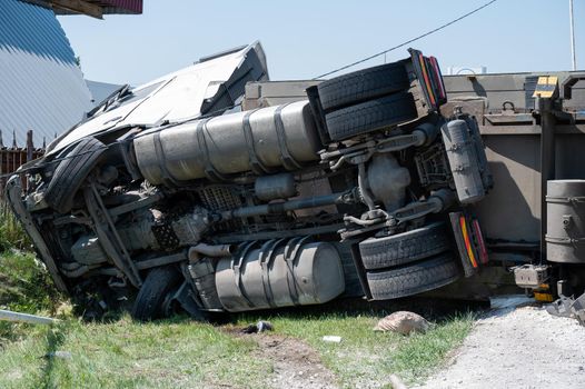 The truck is lying on its side in a car accident on the highway.