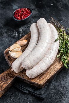 Raw Munich white sausage weisswurst on wooden board. Black background. Top view.