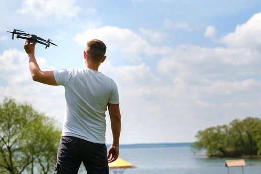 A man with a flying vehicle in his hands, raised to the sky in nature.Launching a drone.