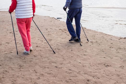 Side view of senior nordic pole walker enjoying nice autumn day outdoors. Outoor shot of active elderly man wearing sport clothes