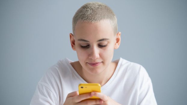 A pensive young woman with a short haircut talks thoughtfully on a mobile phone on a white background.