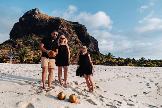 a stylish family in black clothes with coconuts in their hands on the beach of the island of Mauritius.Beautiful family on the island of Mauritius in the Indian ocean.