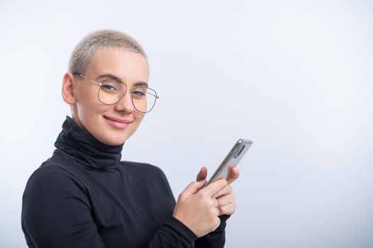 Young caucasian woman with short hair uses a smartphone on a white background