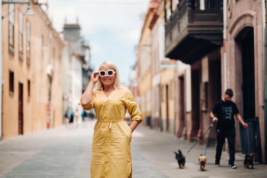 a blonde woman in a yellow summer dress stands on the street of the Old town of La Laguna on the island of Tenerife.Spain, Canary Islands.