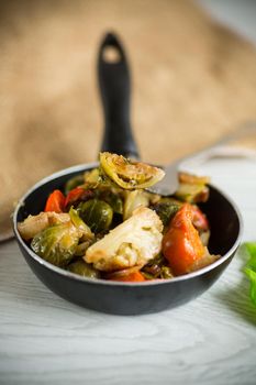 fried brussels sprouts with cauliflower and other vegetables in a frying pan on a wooden table